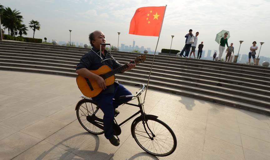 自行车上的音乐人生  他倒骑自行车吹奏口琴、弹吉他……