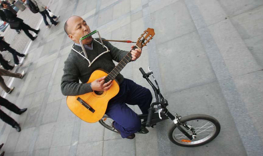 自行车上的音乐人生  他倒骑自行车吹奏口琴、弹吉他……